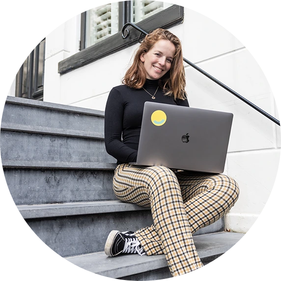 Lachende vrouw op trap met haar laptop met Versio logo